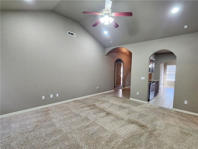 spare room featuring light carpet, visible vents, arched walkways, a ceiling fan, and lofted ceiling