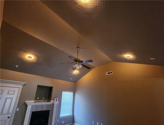 details featuring a ceiling fan, a textured ceiling, visible vents, and a tiled fireplace