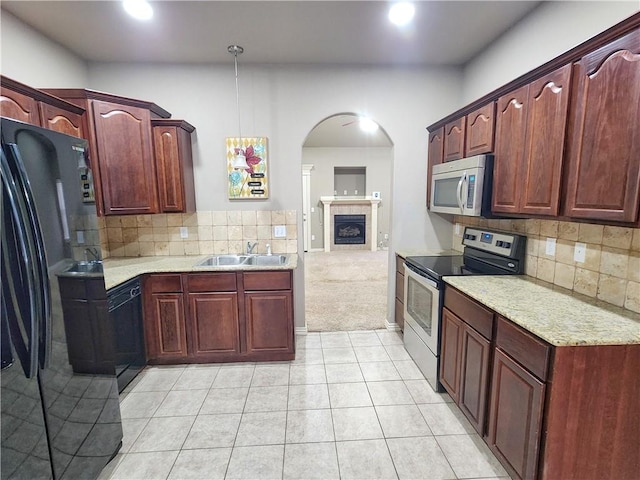 kitchen with a fireplace, decorative backsplash, light carpet, a sink, and black appliances