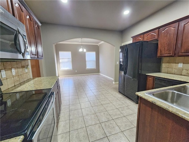 kitchen featuring light tile patterned floors, tasteful backsplash, baseboards, arched walkways, and stainless steel appliances