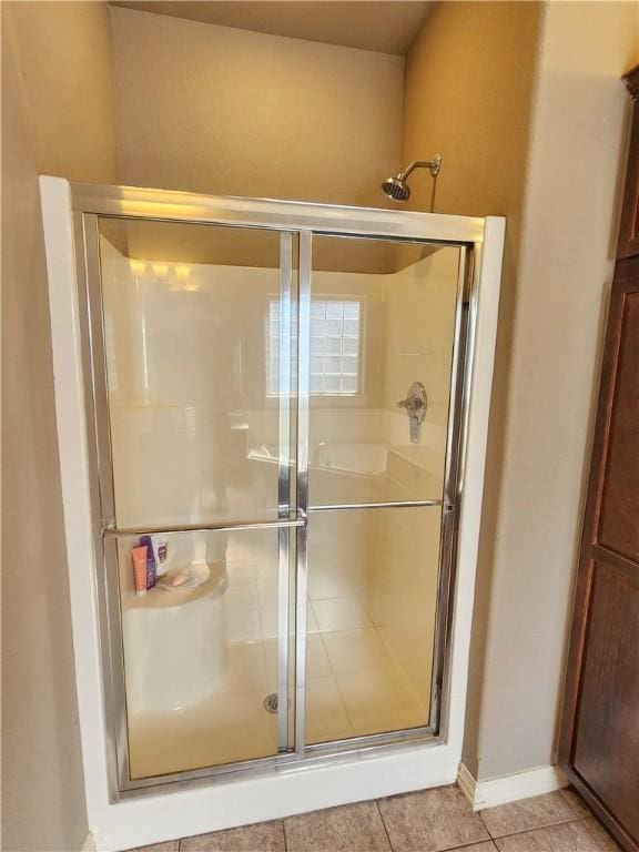 bathroom featuring a stall shower, tile patterned flooring, and baseboards