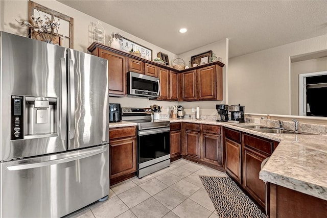 kitchen featuring light tile patterned flooring, a peninsula, a sink, light countertops, and appliances with stainless steel finishes