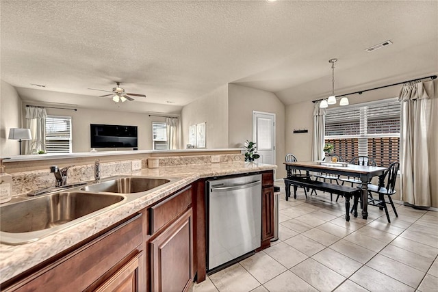 kitchen featuring brown cabinets, decorative light fixtures, stainless steel dishwasher, a sink, and light tile patterned flooring