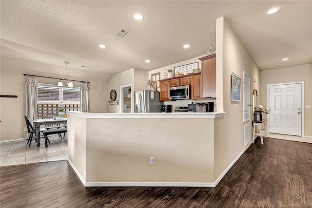 kitchen featuring appliances with stainless steel finishes, recessed lighting, brown cabinetry, and wood finished floors