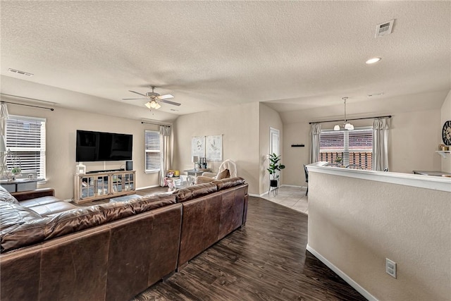 living area featuring baseboards, wood finished floors, visible vents, and a ceiling fan