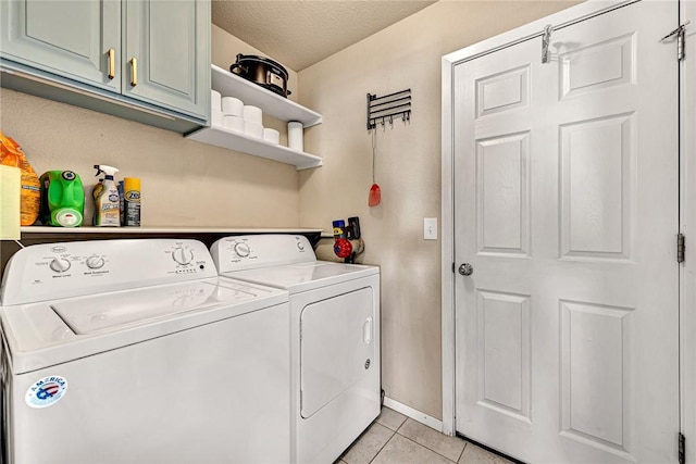 washroom featuring light tile patterned floors, a textured ceiling, baseboards, cabinet space, and washing machine and clothes dryer