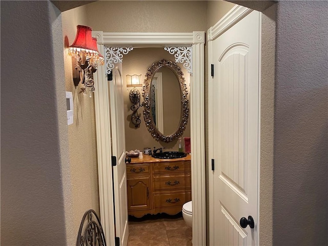 corridor with tile patterned flooring, a sink, and a textured wall