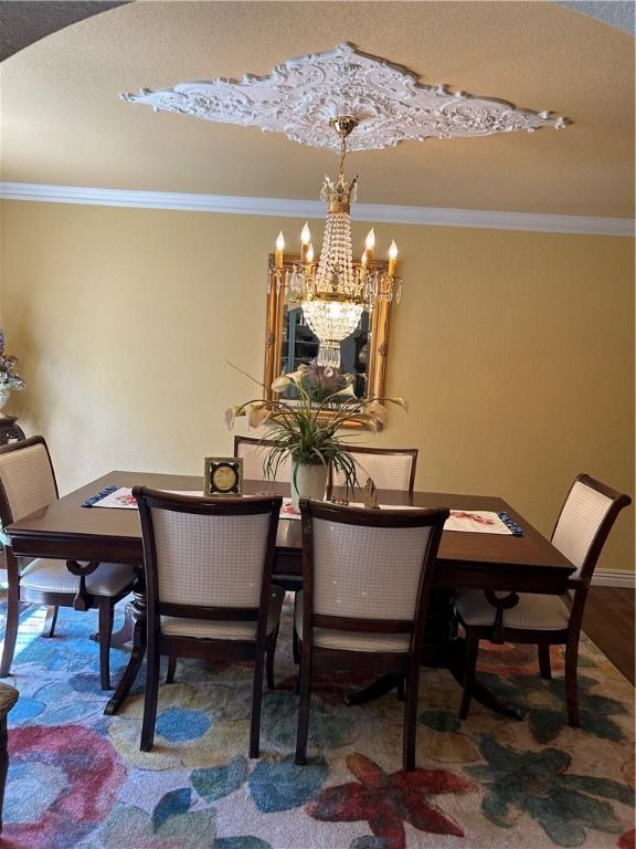 dining room with crown molding, baseboards, wood finished floors, and an inviting chandelier