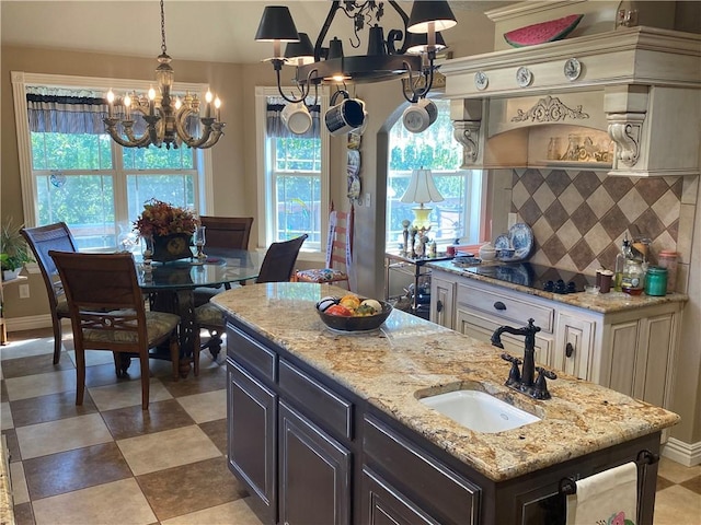 kitchen with tasteful backsplash, a sink, light stone counters, and black electric cooktop