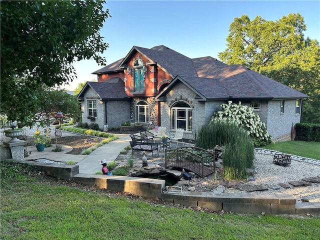 view of front of property featuring a shingled roof, a front yard, and brick siding