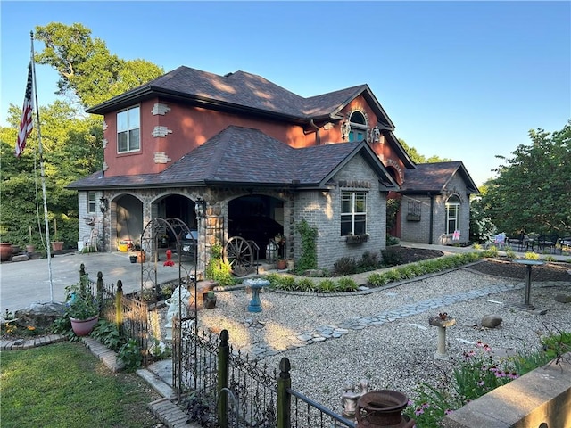 view of front of home featuring driveway, stone siding, a patio area, and fence