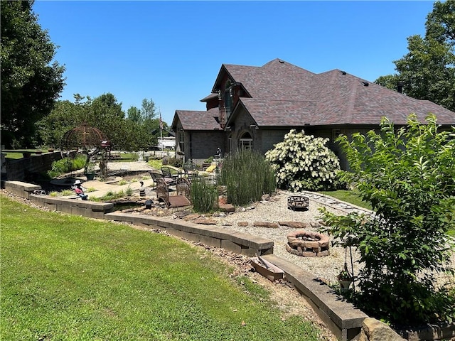 view of property exterior with a patio, an outdoor fire pit, and a lawn