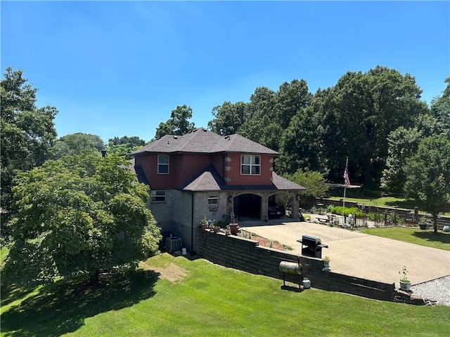 view of front of property featuring driveway, stone siding, central AC, and a front yard