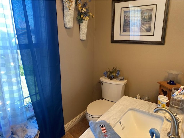 bathroom with tile patterned flooring, baseboards, a sink, and toilet