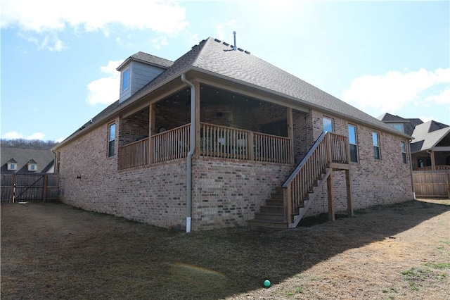 view of side of property with brick siding, stairway, a yard, and fence