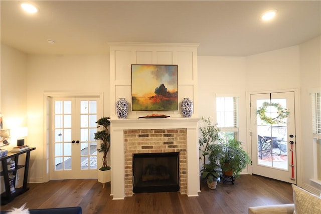 living area with french doors, baseboards, a brick fireplace, and dark wood finished floors