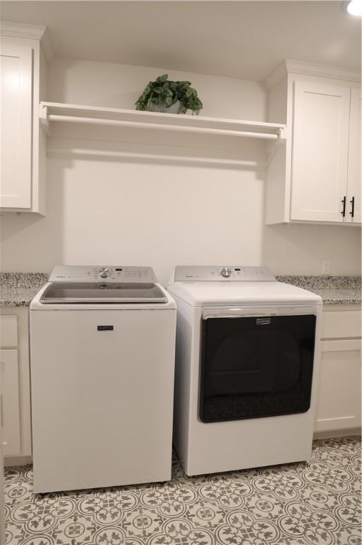 washroom featuring light tile patterned floors, cabinet space, and washer and clothes dryer