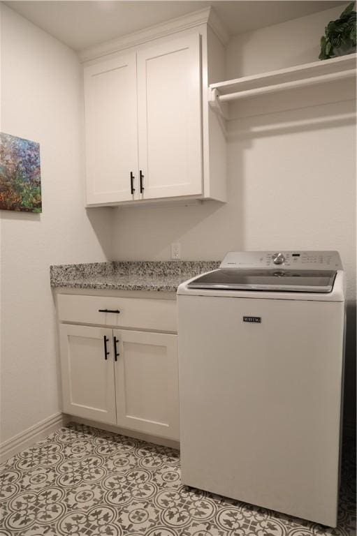 clothes washing area featuring light tile patterned floors, cabinet space, washer / clothes dryer, and baseboards