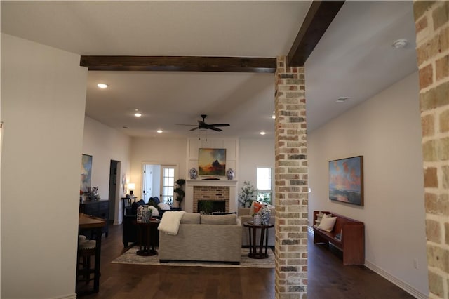 living room featuring beam ceiling, wood finished floors, recessed lighting, a brick fireplace, and ornate columns