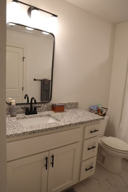 bathroom featuring marble finish floor, vanity, and toilet