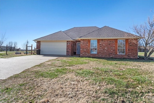 ranch-style house featuring a front yard, roof with shingles, concrete driveway, a garage, and brick siding