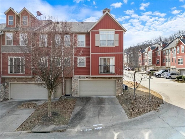 townhome / multi-family property with stone siding, an attached garage, driveway, and board and batten siding