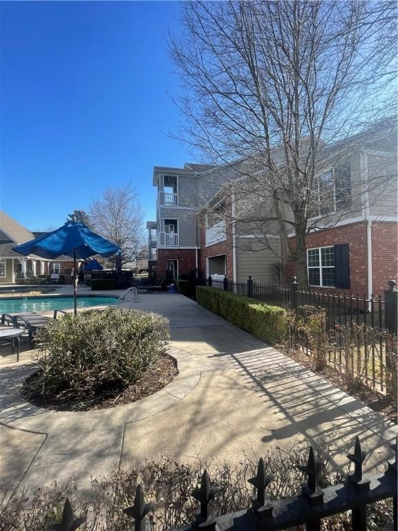 exterior space with brick siding, a community pool, and fence