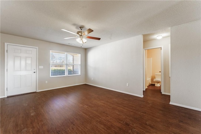 spare room with visible vents, a ceiling fan, a textured ceiling, dark wood finished floors, and baseboards