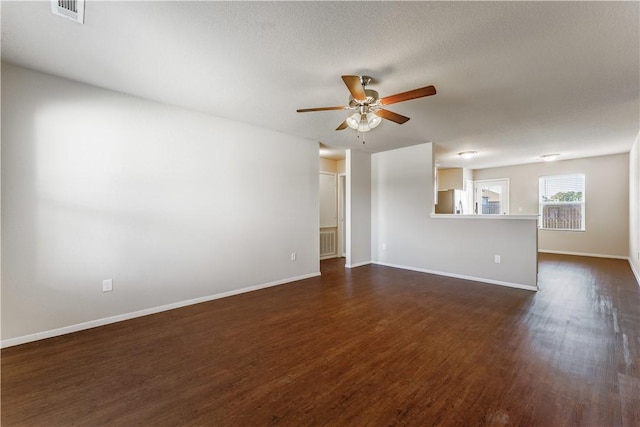 empty room with baseboards, visible vents, dark wood-style flooring, and ceiling fan