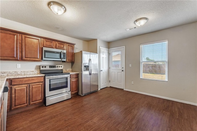 kitchen with dark wood-style floors, visible vents, appliances with stainless steel finishes, and brown cabinets