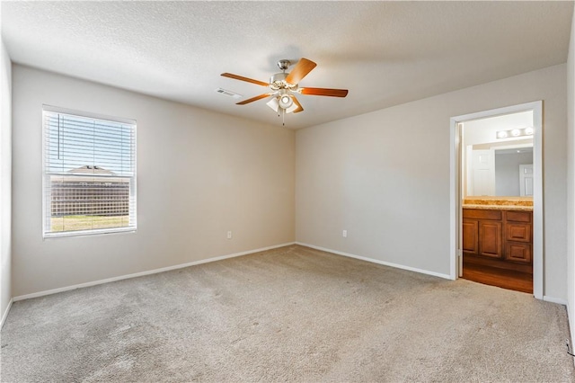 carpeted spare room featuring baseboards, visible vents, a textured ceiling, and ceiling fan