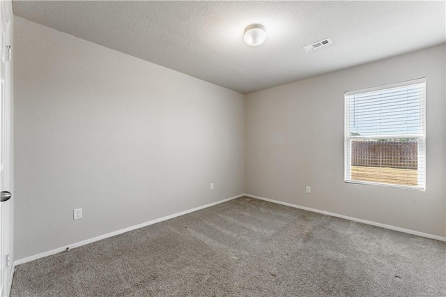 carpeted spare room with visible vents, a textured ceiling, and baseboards