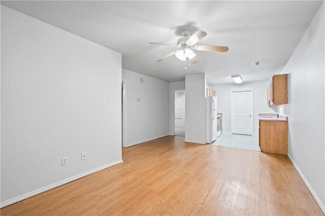 unfurnished living room with baseboards, light wood-style floors, and ceiling fan