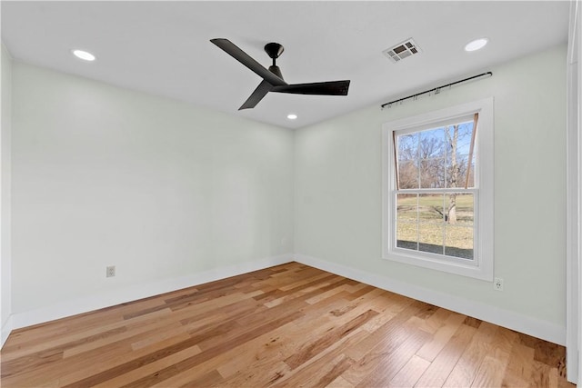 spare room with ceiling fan, visible vents, baseboards, and wood finished floors