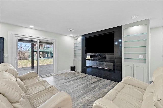 living area with visible vents, built in shelves, wood finished floors, recessed lighting, and baseboards