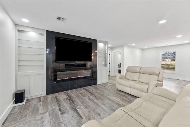 living room with recessed lighting, wood finished floors, visible vents, and baseboards