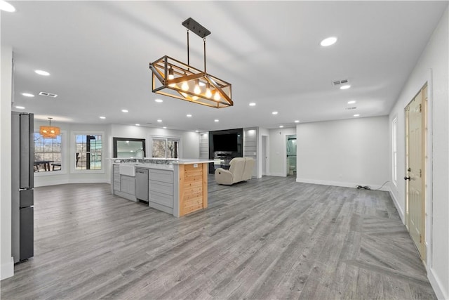 kitchen with open floor plan, light wood-type flooring, freestanding refrigerator, and visible vents