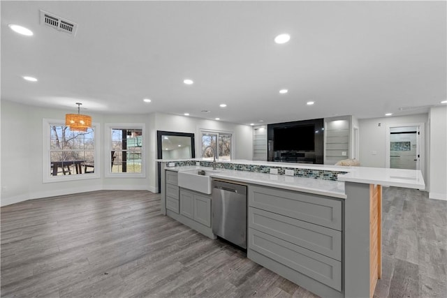 kitchen featuring visible vents, gray cabinets, a sink, stainless steel dishwasher, and light countertops