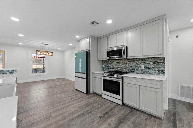 kitchen featuring stainless steel microwave, fridge, gas range oven, and visible vents