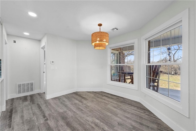 unfurnished dining area with wood finished floors, visible vents, and baseboards