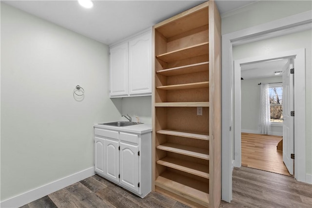 clothes washing area with a sink, baseboards, and dark wood finished floors