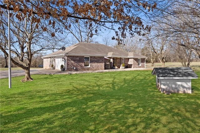 exterior space with an outbuilding, a shed, driveway, a front lawn, and brick siding