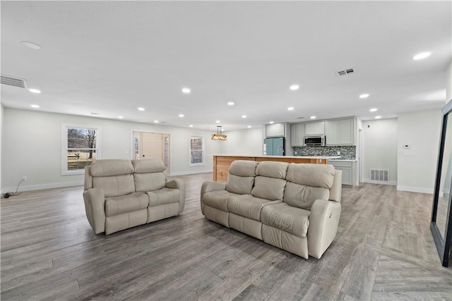 living area with recessed lighting, visible vents, and light wood finished floors