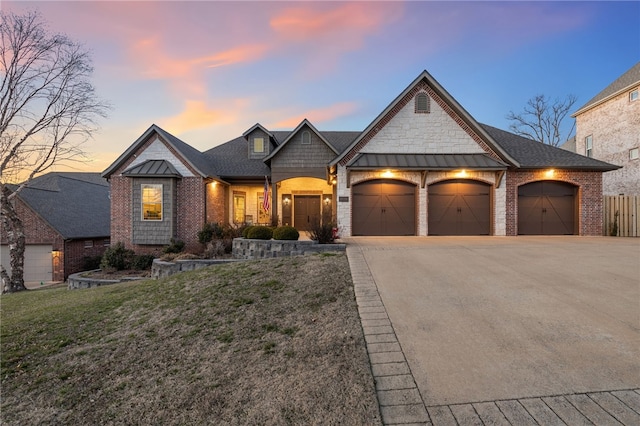 view of front of home featuring brick siding, concrete driveway, a yard, a garage, and a standing seam roof