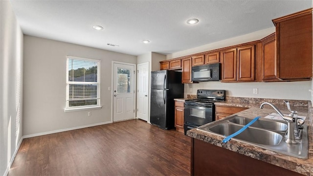 kitchen featuring visible vents, brown cabinets, dark wood-type flooring, black appliances, and a sink