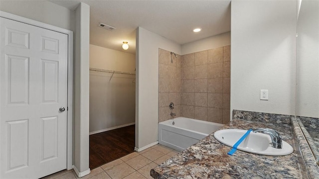 bathroom featuring visible vents, a sink, a walk in closet, tile patterned floors, and shower / bathtub combination