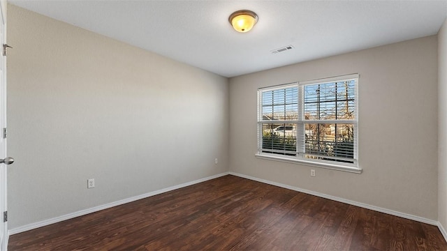 spare room with visible vents, wood finished floors, and baseboards