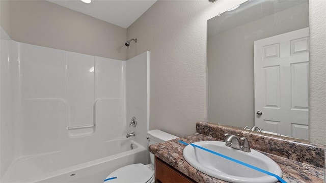 bathroom with shower / bathtub combination, toilet, vanity, and a textured wall