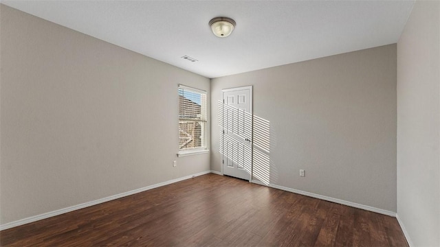 empty room with visible vents, baseboards, and dark wood-style flooring