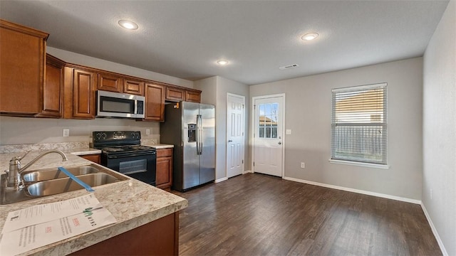 kitchen featuring dark wood-type flooring, light countertops, brown cabinetry, stainless steel appliances, and a sink